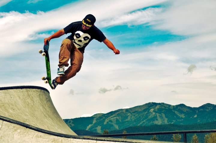 Skateboarding a concrete park feature with mountain in backdrop